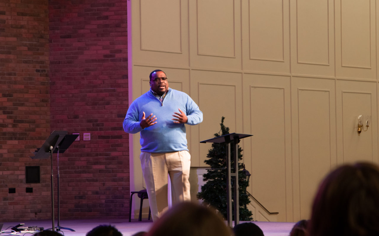 Man speaking on stage in chapel.