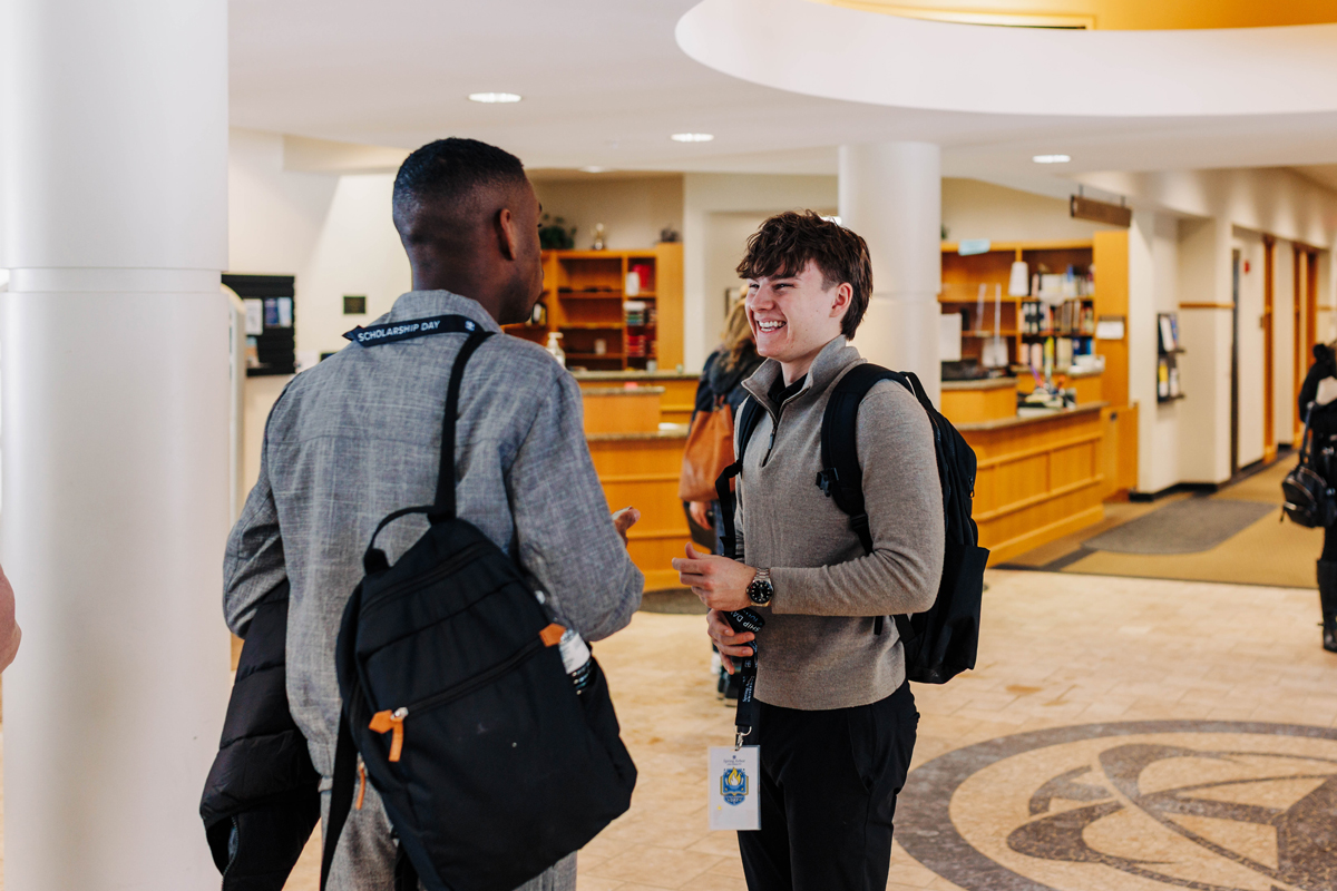 Two students smiling and talking to eachother in the library.