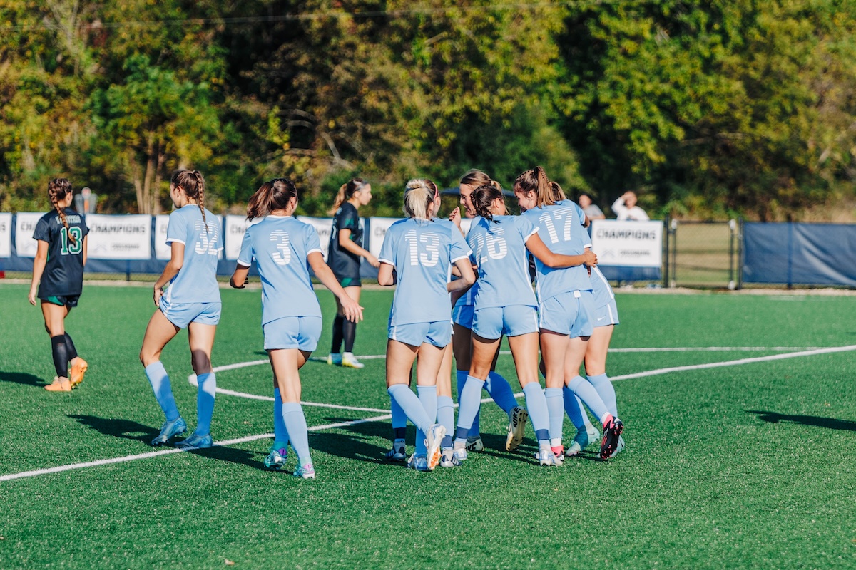 Women's soccer team doing a group hug after a celebration.