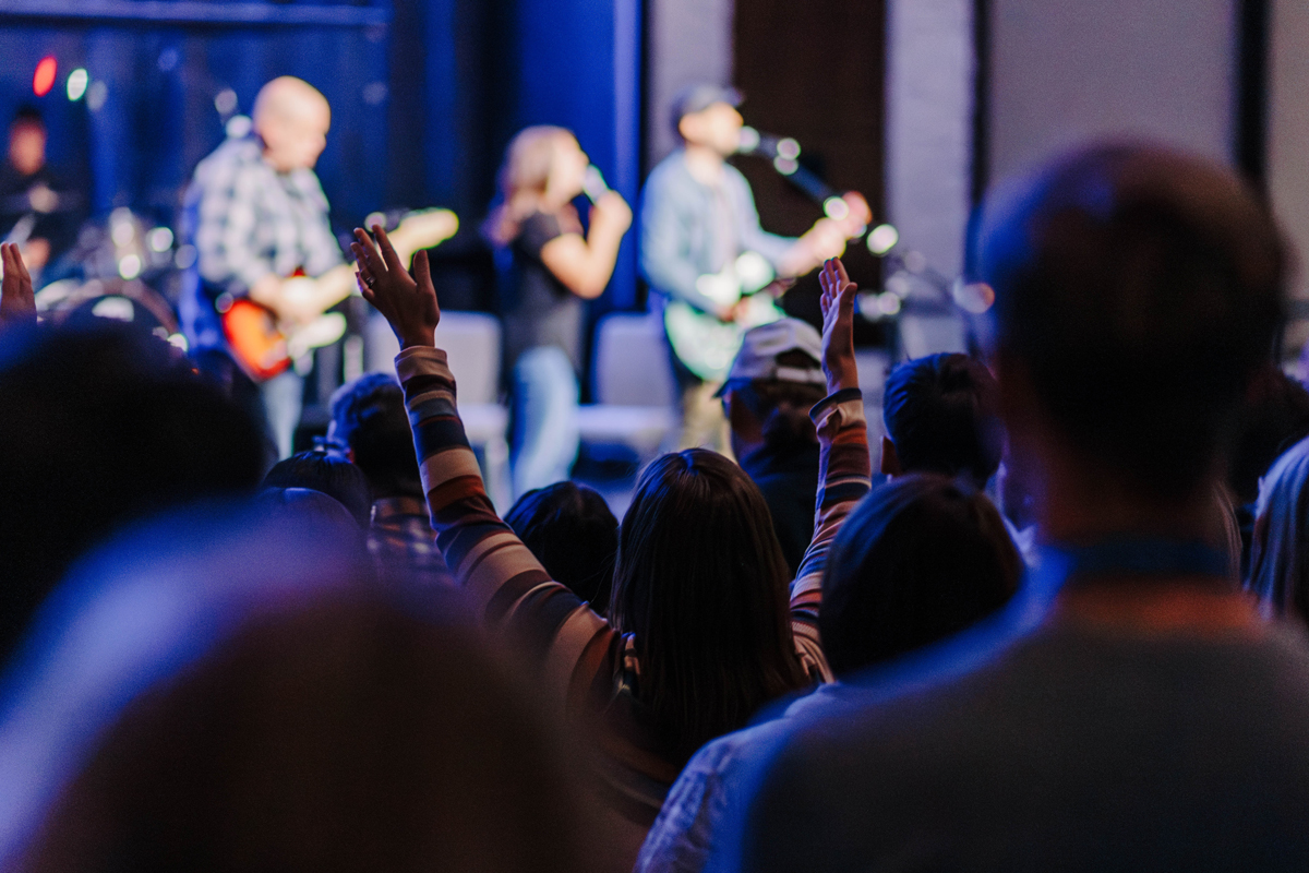 Student with hands up worshing in chapel.