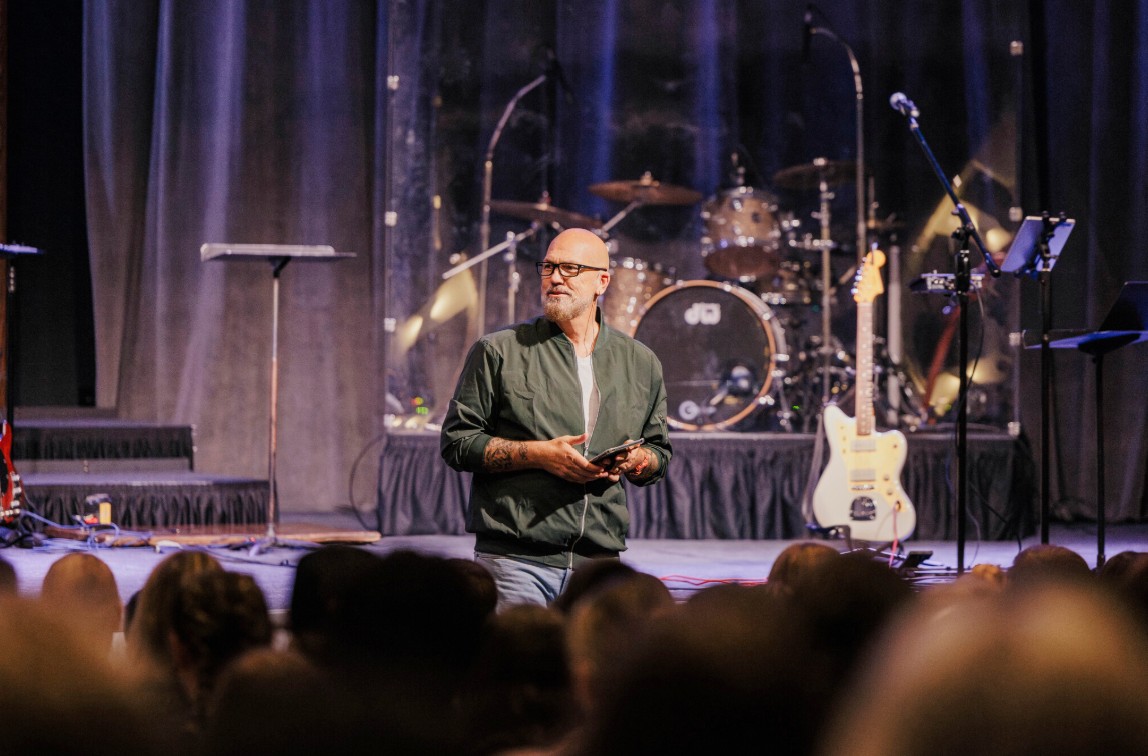 Rob Link standing at the front of the Arbor Church auditorium preaching. 
