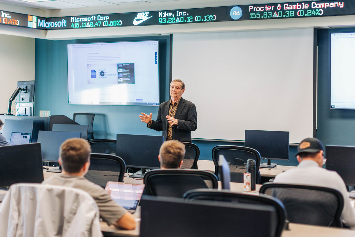 Randall Lewis teaching class in the trading room where the ticker is running.