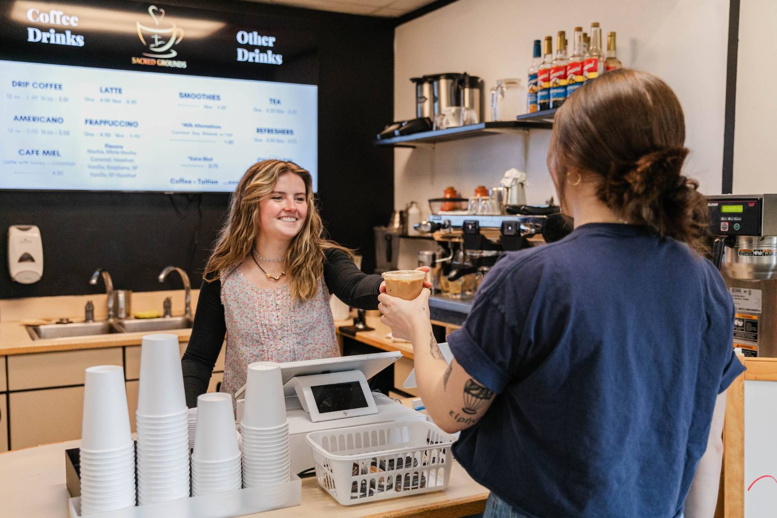 A Barista handing a coffee to a customer