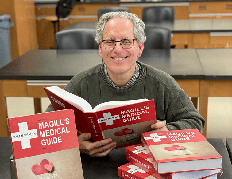 Professional Michael Buratovich, Ph.D. posed with the Magill Medical Guide, 9th edition
